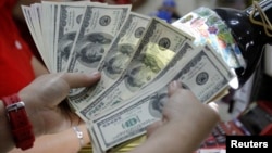 A worker counts U.S. dollar bills, which are being exchanged for Philippine Pesos, inside a money changer in Manila, April 1, 2013. 