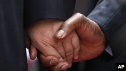 The hand of Chinese President Xi Jinping, left, holds the hand of Zimbabwean President Robert Mugabe, upon his arrival in Harare, Zimbabwe, Tuesday, Dec. 1. 2015