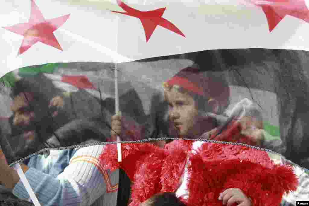 Syrian protesters living in Jordan hold Syrian opposition flags as they shout slogans against Syria's President Bashar al-Assad during a protest outside the Syrian embassy in Amman December 14, 2012. REUTERS/Muhammad Hamed (JORDAN - Tags: POLITICS CIVIL U