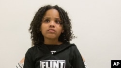 FILE - Mari Copeny, 8, of Flint, Mich. sits on the lap of her mother as they and other Flint residents and supporters wait outside the room where Michigan Gov. Rick Snyder and EPA Administrator Gina McCarthy testify before a House Oversight and Government Reform Committee hearing in Washington, March 17, 2016.