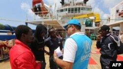 Un migrant africain s'entretient avec un responsable du Haut-Commissariat des Nations Unies pour les réfugiés (HCR) à bord du navire "Sarost 5" amarré dans le port de Zarzis, dans le sud de la Tunisie, le 1er août 2018.