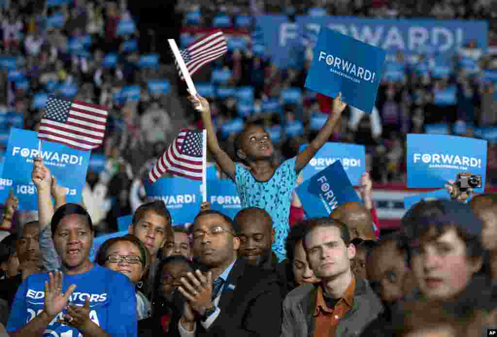 Amara Hayles, 6, of Columbus, sits atop her dad, Marlon Hayles, shoulders and waves a American flag as President Barack Obama speaks at a campaign event at Nationwide Arena in Columbus, Ohio, Nov. 5, 2012. 