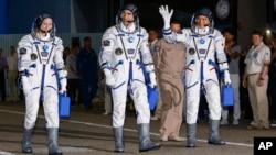 U.S. astronaut Kate Rubins, left, Russian cosmonaut Anatoly Ivanishin, centre, and Japanese astronaut Takuya Onishi, members of the main crew of the expedition to the International Space Station (ISS), walk to report to members of the State Committee prior to the launch of Soyuz MS space ship at the Russian leased Baikonur cosmodrome, Kazakhstan, Thursday, July 7, 2016.