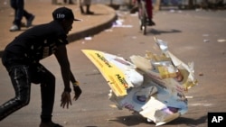 An angry voter smashes a campaign placard of long-time President Yoweri Museveni, outside a polling station where voting material for the presidential election never arrived, at a polling station in Ggaba, on the outskirts of Kampala.