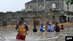 People evacuate their homes through waist-deep flood water in Mogadishu, May 20, 2018, after homes were inundated in Somalia's capital following heavy overnight rainfall. 