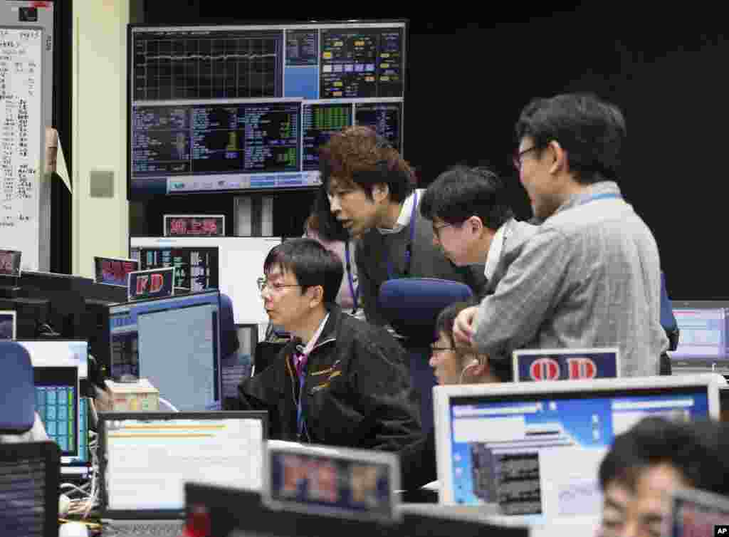 In this photo provided by the Japan Aerospace Exploration Agency (JAXA), staff of the Hayabusa2 Project watch monitors for a safety check at the control room of the JAXA Institute of Space and Astronautical Science in Sagamihara, near Tokyo, Thursday, Feb