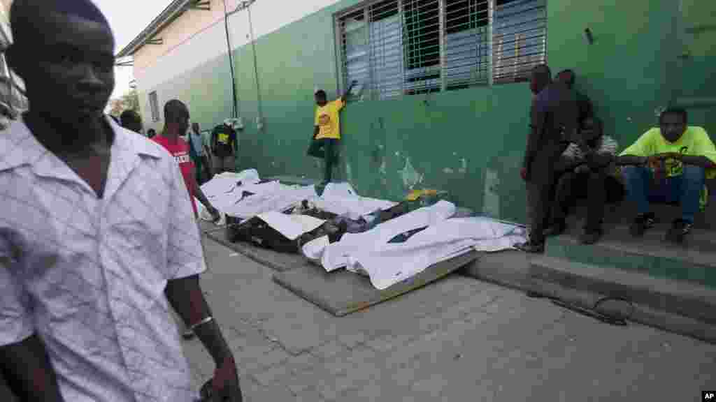 Un homme marche à coté des cadavres de vicitmes de l'accident survenu au festival de Port-au Prince lorsqu'un char au-dessus duquel des musiciens s'étaien tperchés a heurté un cable électrique haute tension, Haiti, le 17 février 2015.