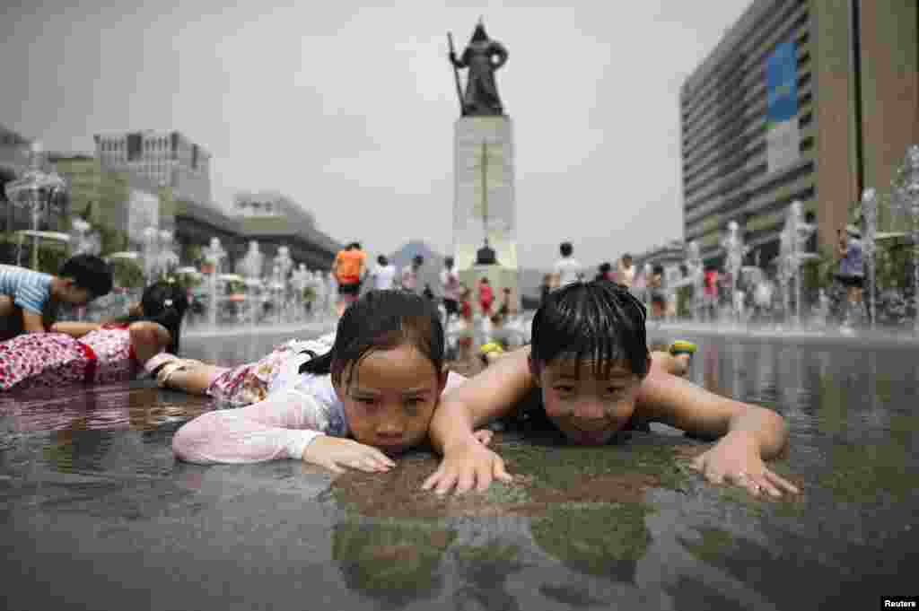 Children play in a fountain to cool down on a hot summer day in front of the General Lee Soon-shin statue in Gwanghwamun, Seoul, South Korea.