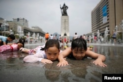 FILE - Children play in a fountain to cool down on a hot summer day in front of the General Lee Soon-shin statue in Gwanghwamun, Seoul July 28, 2014.
