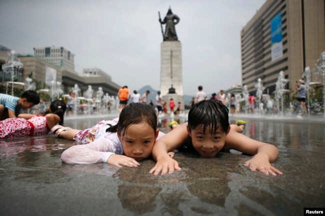 FILE - Children play in a fountain to cool down on a hot summer day in front of the General Lee Soon-shin statue in Gwanghwamun, Seoul July 28, 2014.