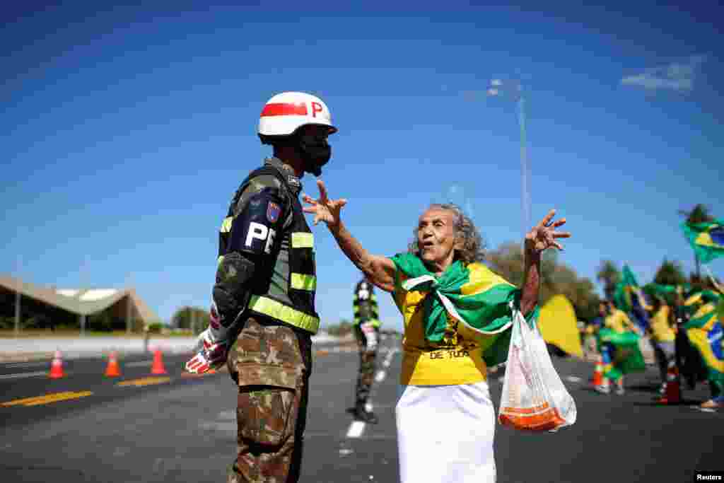 A supporter of Brazil&#39;s President Jair Bolsonaro talks with a soldier during a protest against the country&#39;s Supreme Federal Court, in front of the army headquarters in Brasilia.