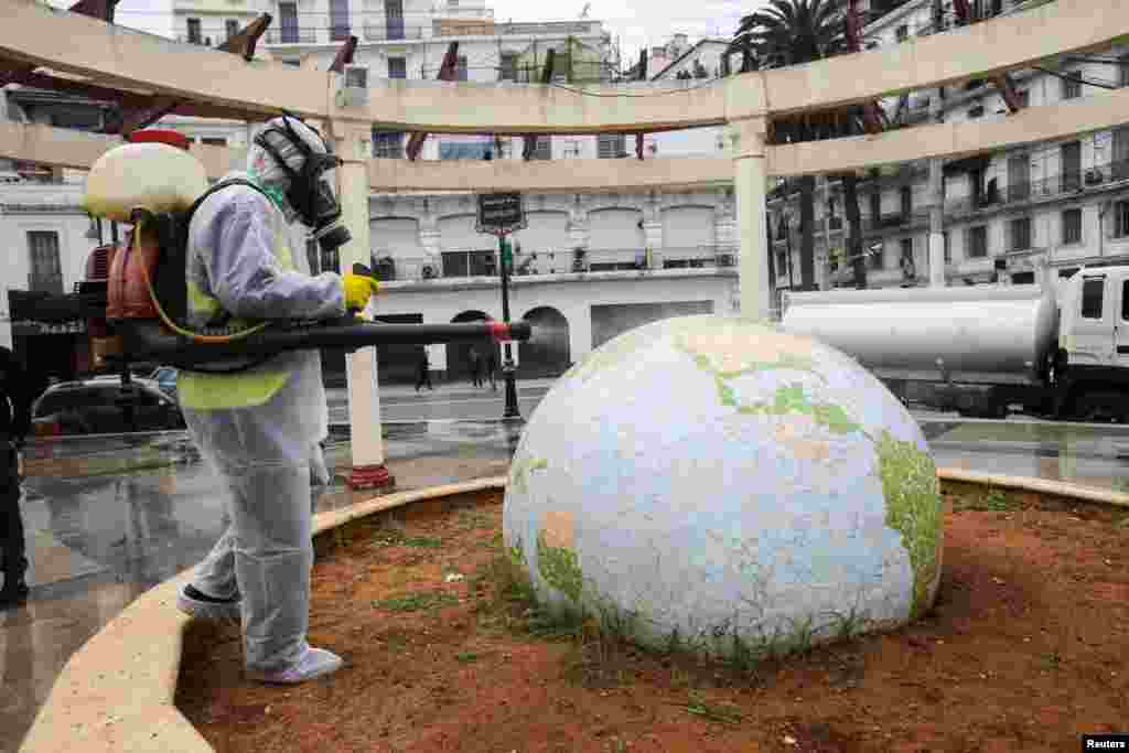 A worker wearing a protective suit disinfects a globe-shaped public garden, following the outbreak of coronavirus disease (COVID-19), in Algiers, Algeria.