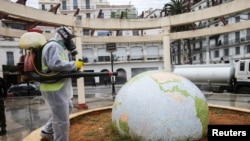 Un travailleur vêtu d'une combinaison de protection désinfecte un jardin public en forme de globe, à la suite de l'épidémie de coronavirus (COVID-19), à Alger, Algérie, le 23 mars 2020. REUTERS / Ramzi Boudina IMAGES TPX DU JOUR - RC2SPF9I75BS