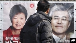 Một người dân dừng lại xem hình 2 ứng cử viên tổng thống Nam Triều Tiên Park Geun-hye (trái), và Moon Jae-in