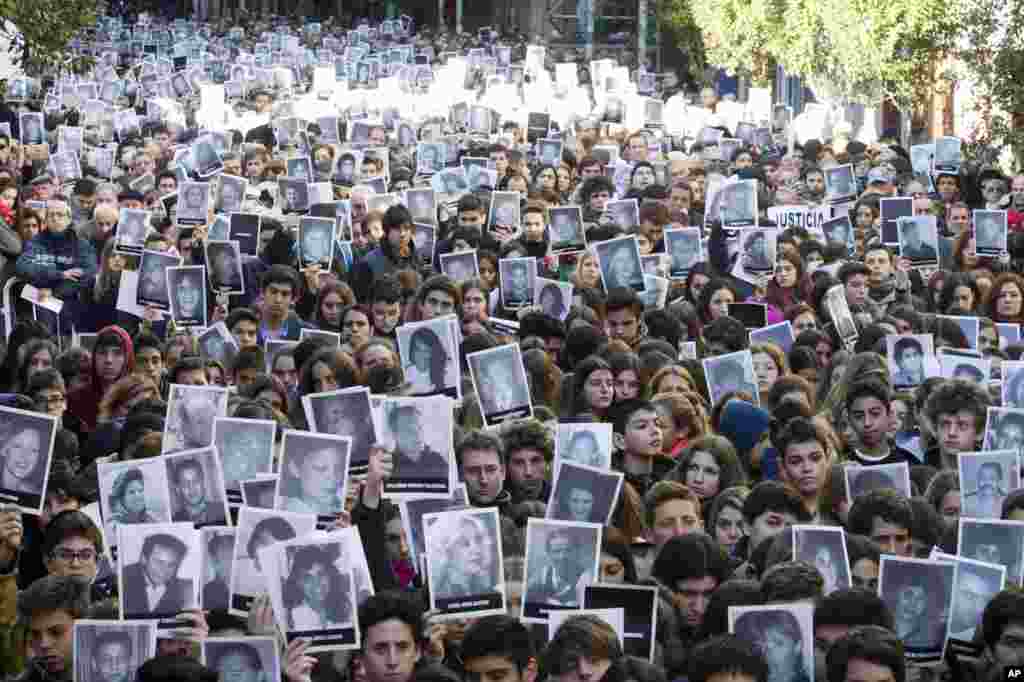 Orang-orang mengusung foto korban pemboman tahun 1994 di balai masyarakat Yahudi pada peringatan 21 tahun serangan tersebut di&nbsp;​Buenos Aires, Argentina. Pemboman yang menyasar warga Argentina kebangsaan Yahudi itu menewaskan 85 orang dan hingga kini belum ditemukan siapa pelakunya.