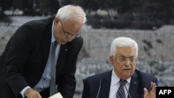 Palestinian president Mahmud Abbas (R) gestures as he signs a request to join 15 United Nations agencies at his headquarters in the West Bank city of Ramallah on April 1, 2014.