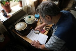 A local resident uses a magnifying glass to read a ballot in his house on the last day of three-day long parliamentary elections in the village of Sintsovo in Nizhny Novgorod Region, Russia. Sept. 19, 2021.