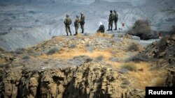 FILE - Members of Iran's Revolutionary guard monitor an area as they stand on a hill top in the Hormuz area of southern Iran, April 24, 2010. 
