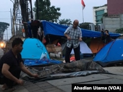 Saat pagi tiba para pengungsi dari Afghanistan melipat tenda yang dijadikan tempat tidurnya di depan rumah detensi imigrasi Jakarta .