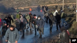 Warga lari dari kejaran polisi di sekitar permukiman Amona di Tepi Barat, 1 Februari 2017. (AP Photo/Sebastian Scheiner). Mahkamah Agung Israel memutuskan pada 2014 bahwa permukiman Amona dibangun di atas tanah pribadi Palestina dan harus dihancurkan sebelum 8 Februari. 