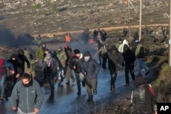 Jewish settlers run from police outside the Amona outpost in the West Bank, Feb. 1, 2017. The military issued eviction orders the day before, telling residents to evacuate Amona within 48 hours and blocked roads leading to the outpost.