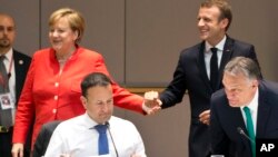 La canciller de Alemania, Angela Merkel, (izquierda) y el presidente de Francia, Emmanuel Macron, en el fondo, durante una desayuno de trabajo en la cumbre de la Unión Europea en Bruselas el viernes, 29 de junio de 2018.