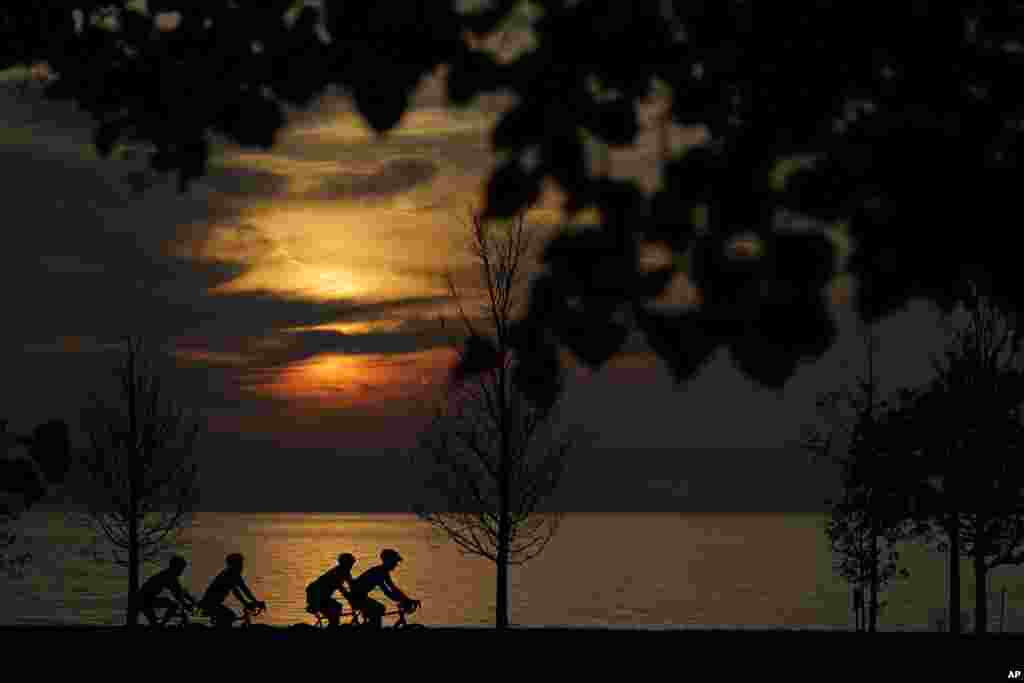 Four cyclists navigate the bike trail along Lake Michigan shortly after sunrise Friday, Aug. 27, 2021, in Chicago. (AP Photo/Charles Rex Arbogast)