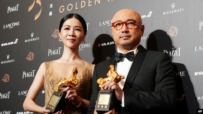 在台湾台北举行的第55届金马奖典礼上的最佳男主角奖得主徐峥（《我不是药神》）和最佳女主角奖得主谢盈萱（《谁先爱上他的》）（2018年11月17日）。