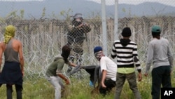 13일 그리스 북부 마케도니아 국경에서 철조망을 넘으려는 이민자들이 경찰과 대치하고 있다. 