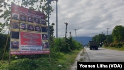 Baliho berisi Daftar Pencarian Orang (DPO) Kelompok Teroris Mujahidin Indonesia Timur (MIT) yang dipajang di sisi jalan Trans Sulawesi di Kecamatan Poso Pesisir, Poso. Jumat (11/12/2020). (Foto: VOA/Yoanes Litha)