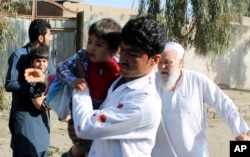 Men carry children away from the site of an explosion in Lashkargah, capital of Helmand province, Afghanistan, Feb. 24, 2018.