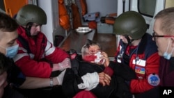 FILE - Ambulance paramedics move a wounded in shelling civilian onto a stretcher to a maternity hospital converted into a medical ward in Mariupol, Ukraine, March 2, 2022.