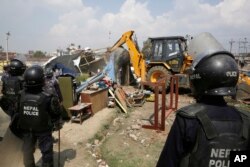 Polisi Nepal merobohkan rumah sementara di tempat penampungan korban gempa di pusat kota Kathmandu, Nepal, Selasa, 14 Maret 2017. (Foto: AP)