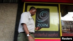 FILE - A man uses his mobile phone as he walks past a Zain customer care shop in Nairobi, Kenya, Feb. 15, 2010. Political activists in South Sudan have accused Zain South Sudan of disrupting their phone service ahead of a planned protest.