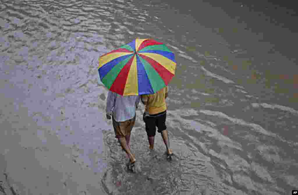 Men walk under an umbrella down a flooded street during a monsoon downpour in Lahore, Pakistan, September 16, 2011. (Reuters)