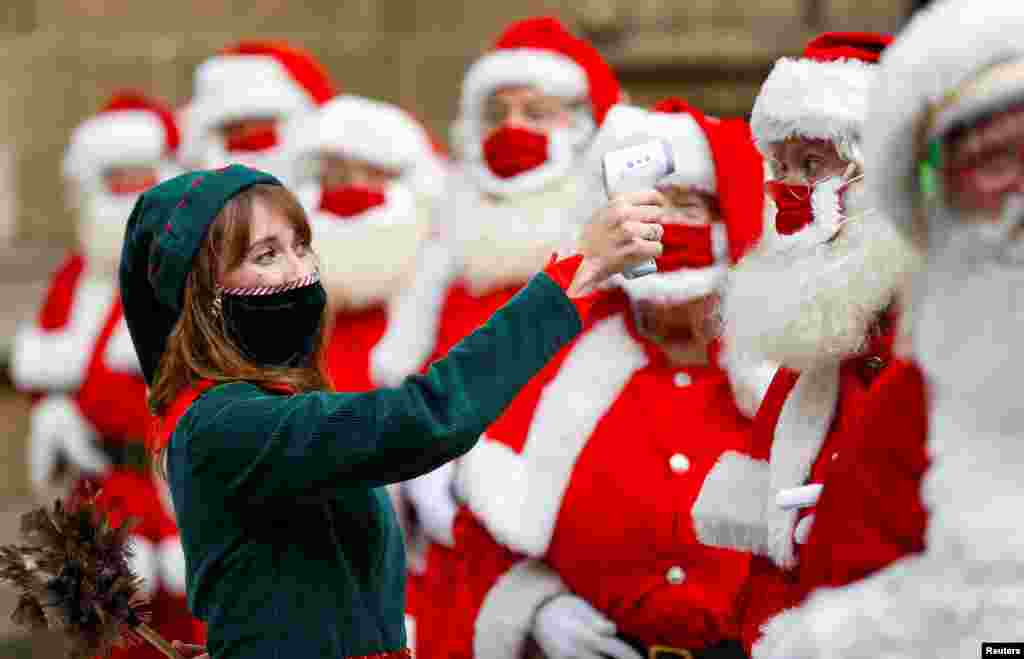 A woman dressed as an elf takes the temperatures of attendees of the Ministry of Fun Santa School outside Southwark Cathedral, in London, Britain.