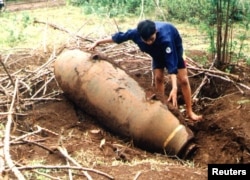 A Vietnamese bomb disposal expert inspects a U.S.-made Vietnam War-era bomb found in An Nha village in the central province of Quang Tri, Vietnam, Aug. 2, 2001.