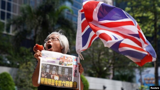 FILE - A supporter holds an apple and a copy of the Apple Daily newspaper outside the court to support media mogul Jimmy Lai, founder of Apple Daily, over charges related to an unauthorized assembly, Oct. 1, 2019, in Hong Kong, May 28, 2021. 