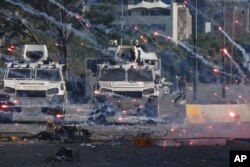 Fireworks launched by opponents of Venezuela's President Nicolas Maduro land near Bolivarian National Guard armored vehicles loyal to Maduro, during an attempted military uprising in Caracas, April 30, 2019.