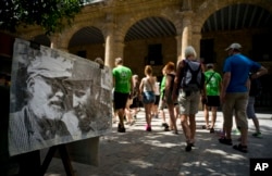 Tourists walk next to an weathered old photo of Ernest Hemingway and Fidel Castro in Havana, Cuba, March 14, 2016. U.S. President Barack Obama will travel to Cuba on March 20.