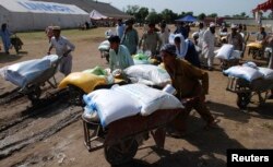 FILE - People fleeing from the military offensive against Pakistani militants in North Waziristan walk away with wheelbarrows of relief handouts from the World Food Program at a distribution point for internally displaced persons in Bannu, located in Pakistan's Khyber-Pakhtunkhwa province, July 6, 2014.