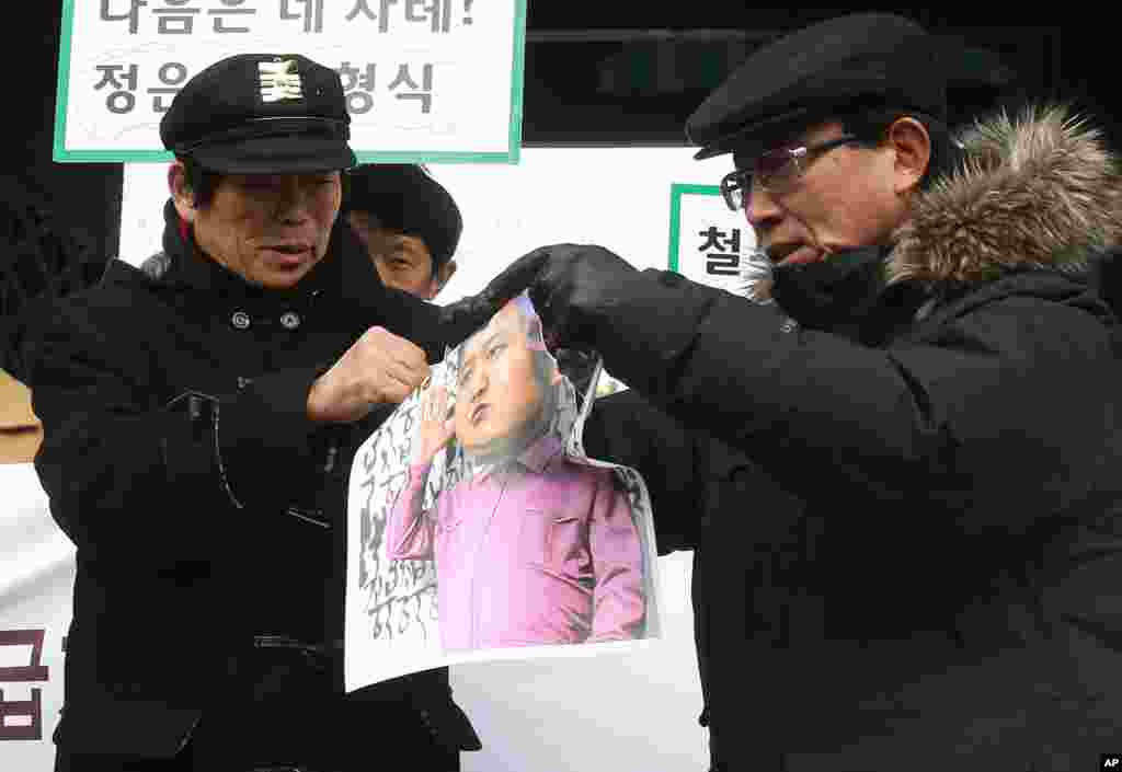 North Korean defectors tear a caricature of North Korean leader Kim Jong Un during an anti-North Korea rally marking the second anniversary of Kim Jong Il's death, Seoul, Dec. 17, 2013. 