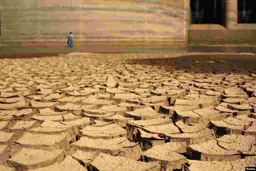 A worker of SABESP, a Brazilian enterprise of Sao Paulo state, that provides water and sewage services to residential, commercial and industrial areas, walks through a dry Jaguary dam as a result of a long drought period that hit the state in Braganca Paulista, 100 km from Sao Paulo. The heat plus a severe drought has fanned fears of water shortages, crop damage, and higher electricity bills that could drag down the economy during an election year for President Dilma Rousseff.