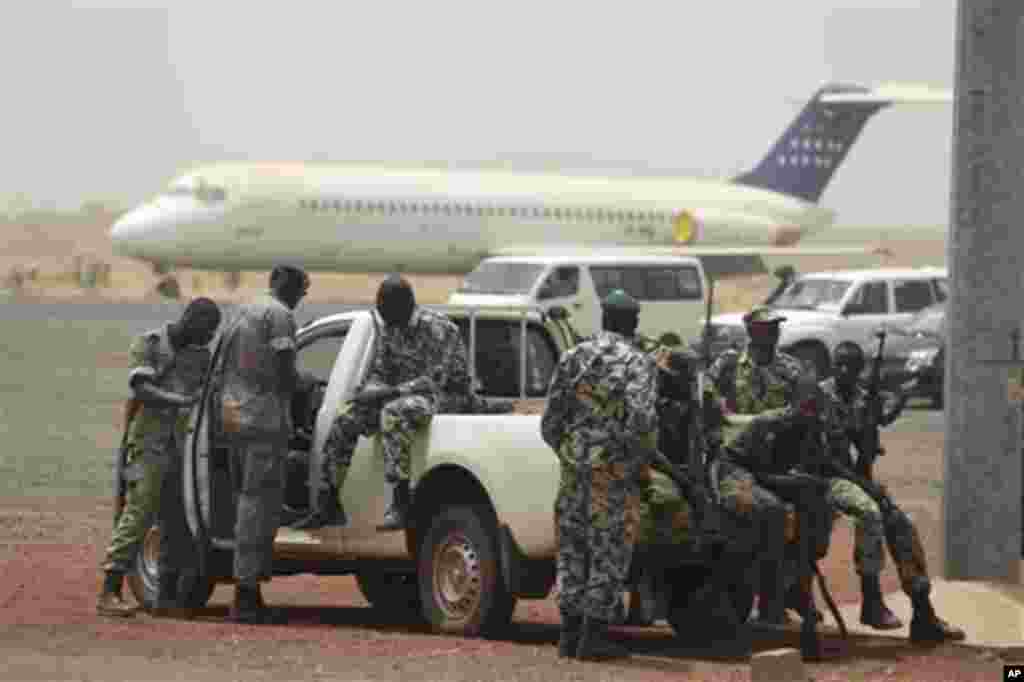 Soldiers sit guard on the tarmac of the international airport, where coup leader Capt. Amadou Haya Sanogo had been due to meet a delegation of West African presidents, in Bamako, Mali, Thursday, March 29, 2012.