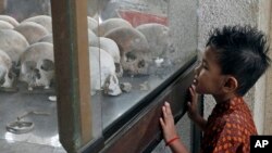 A boy looks at a pile of skulls in a stupa at Choeung Ek memorial on the outskirts of Phnom Penh, Cambodia, April 17, 2014.