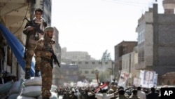 Two Yemeni army soldiers who defected stand guard as protesters march during a demonstration demanding the prosecution of Yemen's President Ali Abdullah Saleh in Sanaa, Yemen, December 1, 2011.
