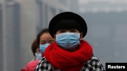 一名女子在北京的雾霾中戴着口罩行走。（资料照片）