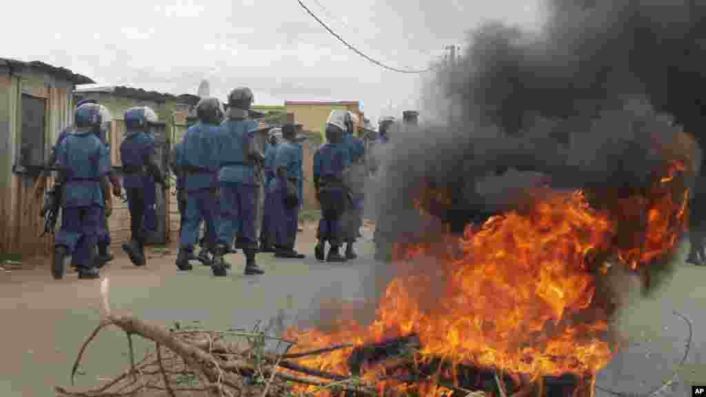 La police anti-émeute burundaise, en patrouille, dépasse un pneu en flamme que des manifestants ont brulé sur une rue de la capitale Bujumbura, Burundi, dimanche 26 avril 2015.