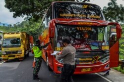 Para petugas memeriksa sebuah bus penumpang pada hari pertama penerapan larangan mudik nasional untuk mencegah penyebaran pandemi COVID-19, di Tasikmalaya, Jawa Barat, 6 Mei 2021. (Foto: Adeng Bustomi/ Antara Foto via Reuters)