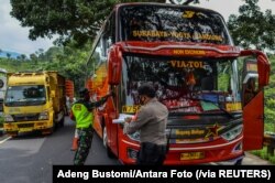 Para petugas memeriksa sebuah bus penumpang pada hari pertama penerapan larangan mudik nasional untuk mencegah penyebaran pandemi COVID-19, di Tasikmalaya, Jawa Barat, 6 Mei 2021. (Foto: Adeng Bustomi/ Antara Foto via Reuters)